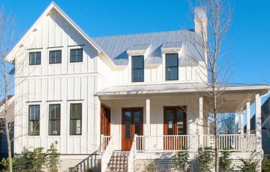 Modern farmhouse-style home with white board and batten siding, a metal roof, and a covered front porch with wooden doors